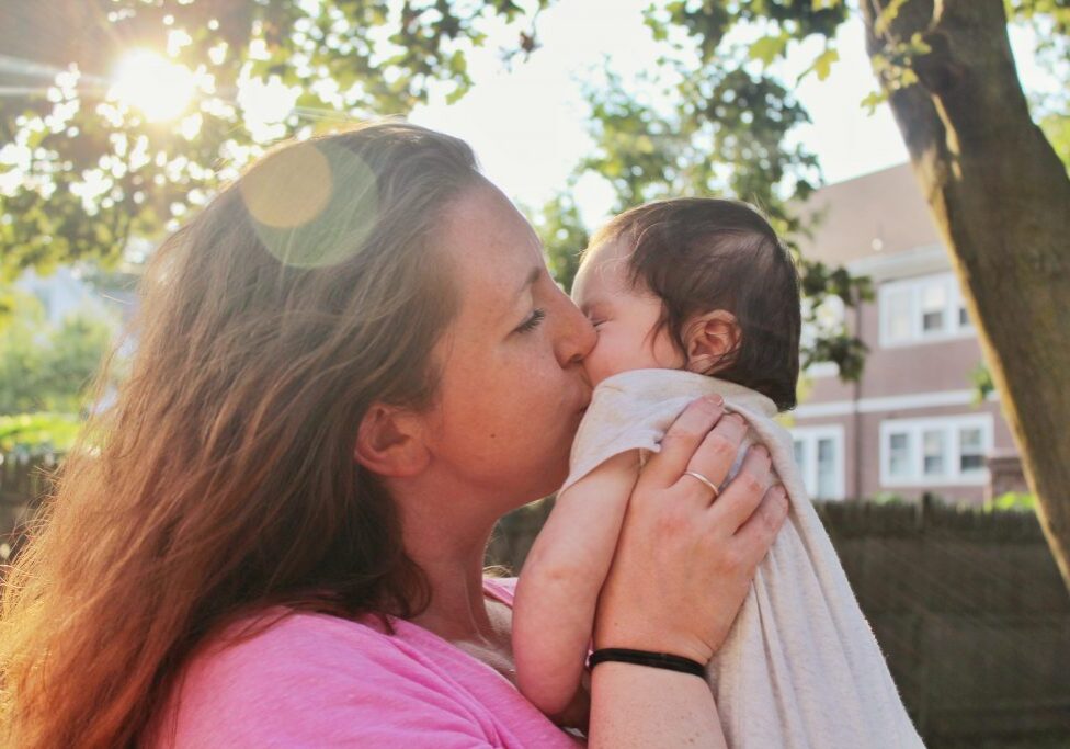 woman holding and kissing young baby